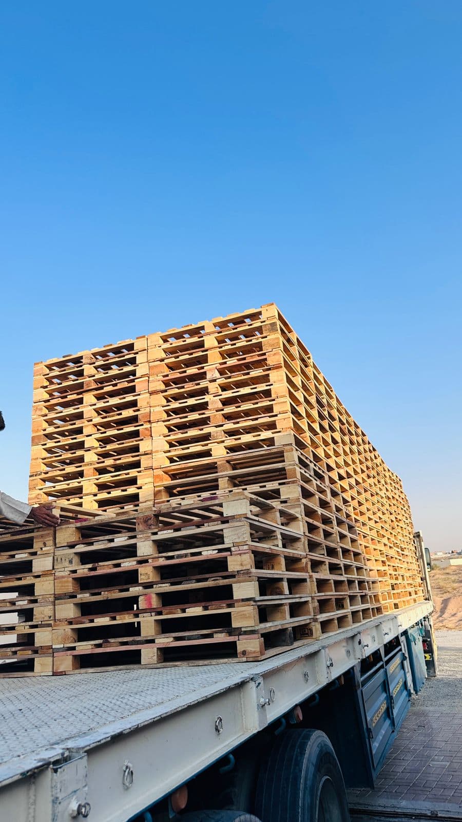A trailer loaded high with wooden pallets ready to leave the yard