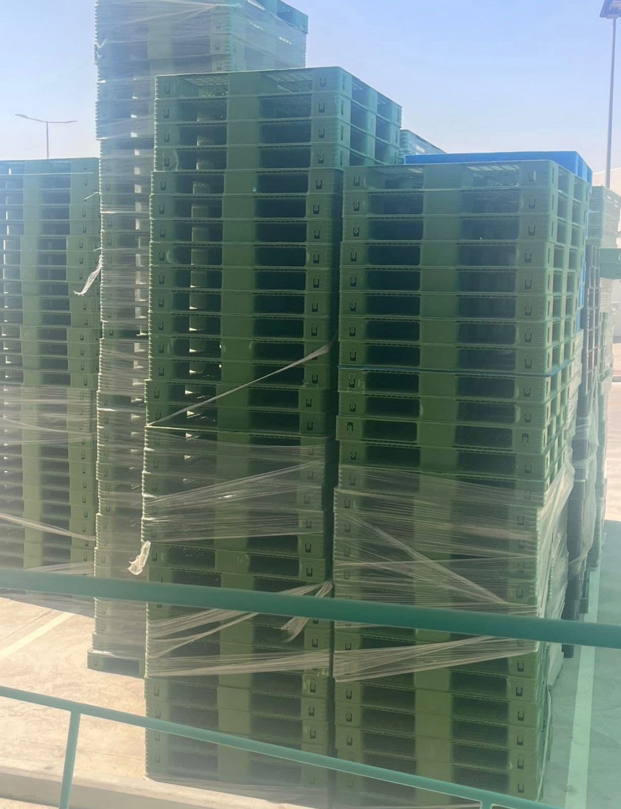 Wrapped stacks of green plastic pallets ready for dispatch